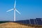 Wind turbine and solar panels in fields against blue sky producing renewable energy