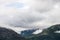 Wind turbine stands on mist-enshrouded mountain peaks overlooking verdant Northern European valley