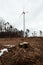 Wind turbine station in destroyed and deforested forest with tree stump in foreground -environmental problem concept