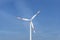 Wind turbine with three arms for electricity production standing in West Germany with a blue sky background.