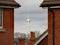 A wind turbine visible between two houses. The turbine is situated by the side of the M4 motorway on the Green Park business