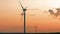 Wind turbine in wheat field at sunset, propellers of windmills on sunset sky background