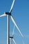 Wind turbines close up against a clear blue sky.