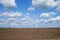 Wind turbines and environmental infrastructure isolated against blue sky with copy space on an empty energy farm