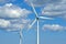 Wind turbines and environmental infrastructure isolated against blue sky with copy space on empty energy farm