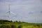 Wind turbines reflecting sun on a cloudy day in green rolling fields