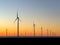 Wind turbines at sunset. Offshore wind mills, wind farm, generating electricity, rotating at orange sunrise