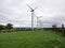 Windfarm with rows of windmills and sheep grazing below