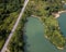 A winding asphalt road traverses a large body of water near a river in Malaysia.