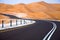 Winding black asphalt road through the sand dunes of Liwa oasis, United Arab Emirates