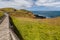 Winding boardwalk among green blossoming hills at the coastline