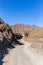 Winding gravel dirt road through rocky limestone Hajar Mountains in United Arab Emirates