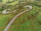 Winding narrow road on a hill in Burren, Ireland. Aerial drone view. Green fields and small trees around the pass