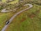 Winding narrow road on a hill in Burren, Ireland. Aerial drone view. Green fields and small trees around the pass