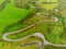 Winding narrow road on a hill in Burren, Ireland. Aerial drone view. Green fields and small trees around the pass