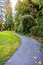 A winding path in a park with trees, bushes, green grass