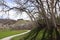 A winding path past twisted gnarly trees with a mansion on the hills in the background