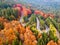 Winding road from high mountain pass, in autumn season, with orange forest