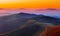 Winding road through meadows of mountain range at sunset