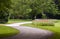 A winding road in the park with green grass and poppy flowerbed on the background