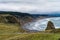 A winding road passes a sea stack on the beach at Cape Blanco State Park in Oregon, USA