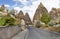 A winding road from paving stones passes near the stone cone houses in the ancient rocks of Goreme, Kappadoki.