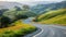 The winding road of a snaking highway leads up a steep incline revealing a picturesque countryside with rolling hills