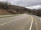 Winding roadway in mountainous terrain. Unrecognizable people walking along road in distance.