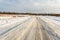 The winding snow-covered road goes into the horizon. Sunny winter day with blue skies and small clouds