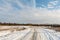 The winding snow-covered road goes into the horizon. Sunny winter day with blue skies and small clouds