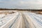 The winding snow-covered road goes into the horizon. Sunny winter day with blue skies and small clouds