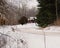 Winding snow-covered road leading to a rural house, with road signs and trees, in Michigan US