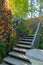 A winding steep staircase with stone steps and iron rails against the background of beautiful climbing plants