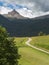 Winding Walking Footpath through Meadows, Italian Alps Mountains in background