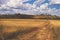 A winding yellow road against the background of summer day cloudy sky in the fields and hills reserved park places of Russia