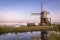 Windmill along the waterside in the western part of The Netherlands with fogbanks over the fields