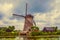 Windmill, bushes and canal in a cloudy day at Kinderdijk.