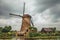 Windmill, bushes and canal in a cloudy day at Kinderdijk.