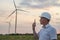 Windmill engineer talking with portable radio transmitter outdoor on wind turbines background. A man in a helmet supervises the