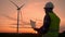 Windmill engineer watching wind turbines in operation on a laptop