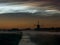 Windmill, fog banks and bright noctilucent clouds NLC over the dutch landscape during a midsummer night