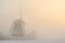 Windmill in a foggy winter sunrise