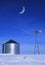 Windmill and Grain Silos in Winter Snow on Farm for Agricultural Farming with Crescent Moon