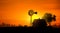 Windmill, house and tractor at sunset.