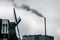 Windmill and industrial chimney of Olam Cocoa Factory in a dark and cloudy day in Zaanse Schans The Netherlands with pollution