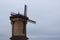 A windmill made of wooden beams against a cloudy autumn sky. A tall building made of wood