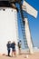 Windmill with man climbing on the blades to install the cloth to make it work and photographers and video makers doing the