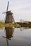 A windmill next to a house in kinderdijk with beautiful water reflection