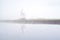 Windmill reflected in river and dense fog