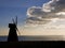 Windmill silhouette blowing away dark clouds